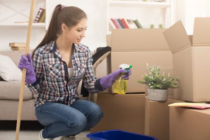A person cleaning, opened boxes in a room after a house move.