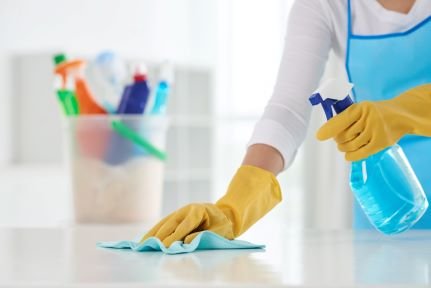 Person wiping surface with cleaning product and gloves on